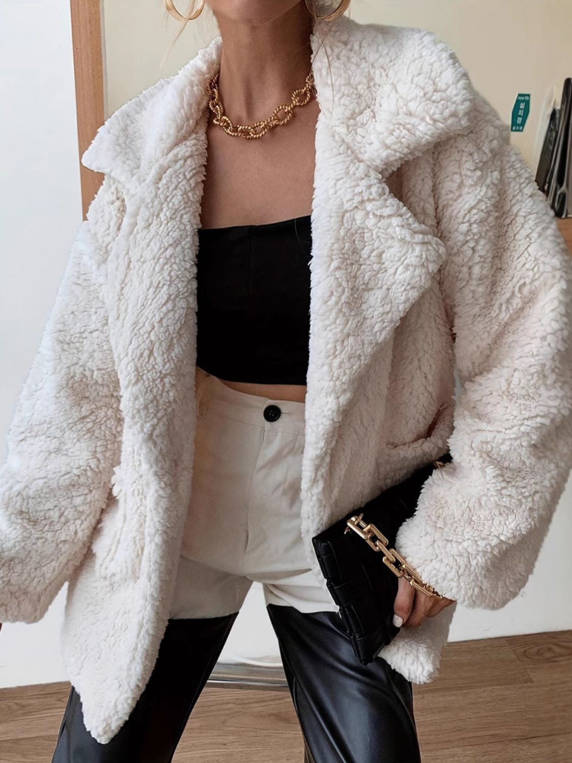 White faux shearling teddy coat over black crop top and high waist shorts held with black clutch affordable outerwear for women