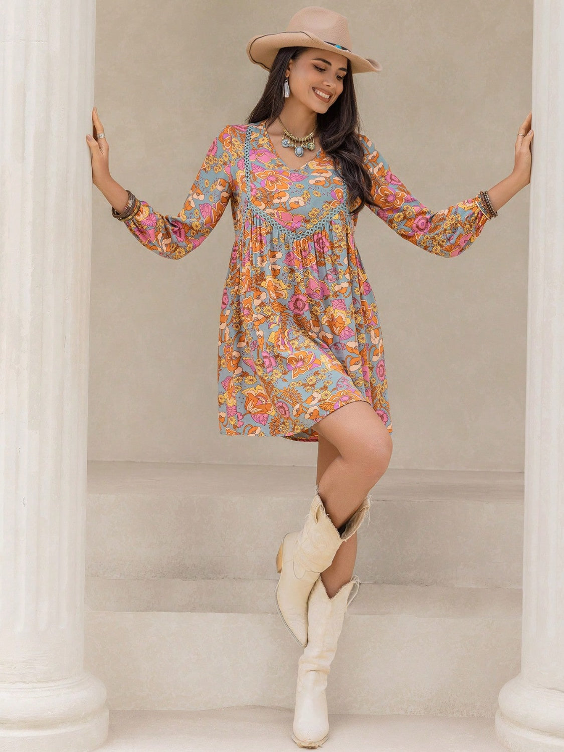 Smiling woman in floral boho dress with hat and white cowboy boots outfit of the day inspiration