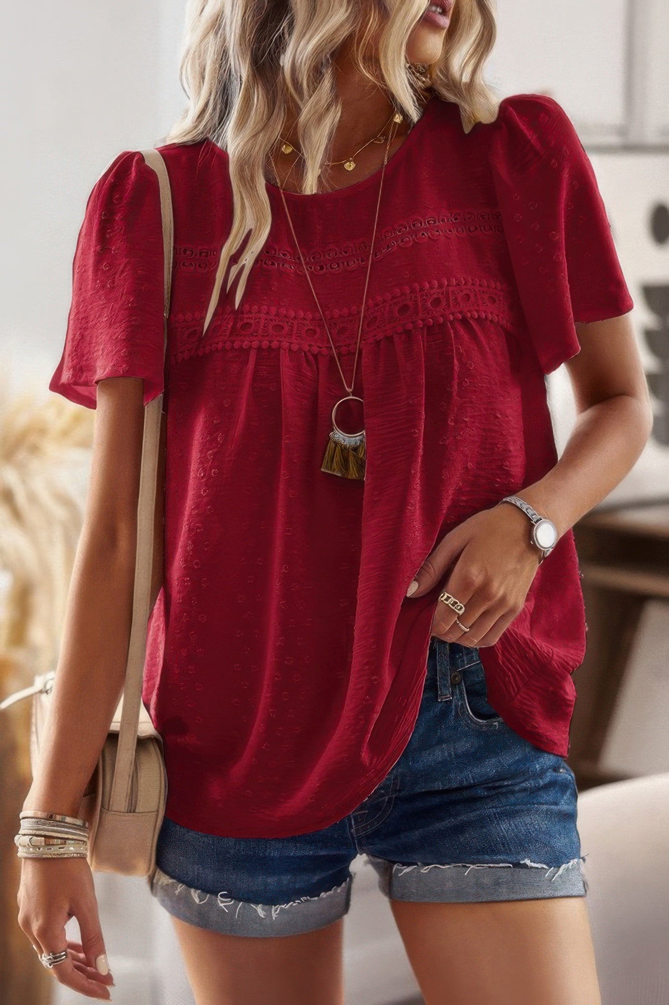Woman wearing plus size solid short sleeve top in red with lace trim puff sleeves paired with denim shorts