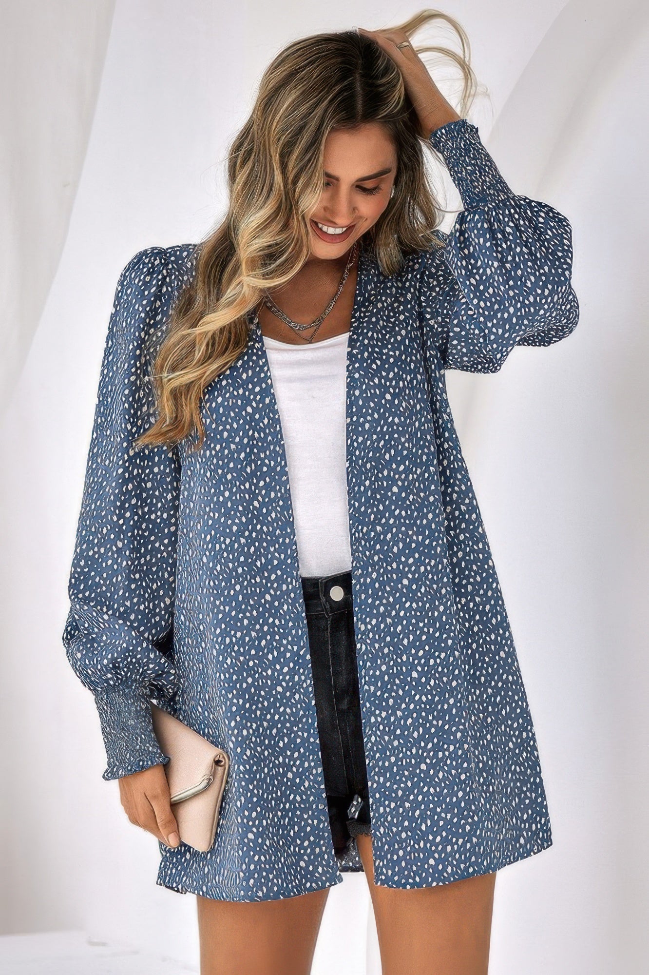 Woman wearing blue leopard print front open top with puff sleeves over white tee and black shorts