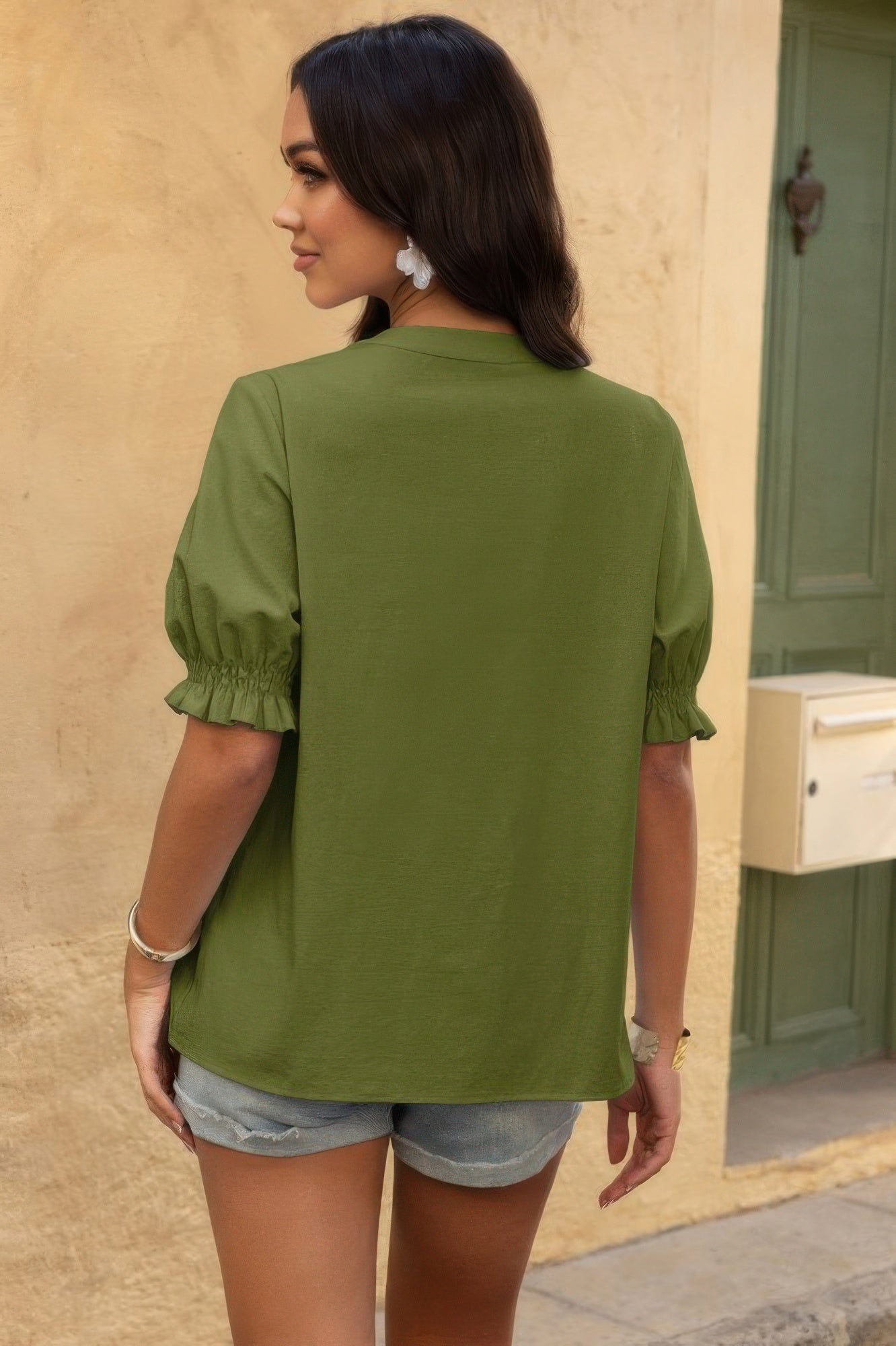 Woman wearing olive green boho v neck button down shirt with puff sleeves and smocked cuffs back view