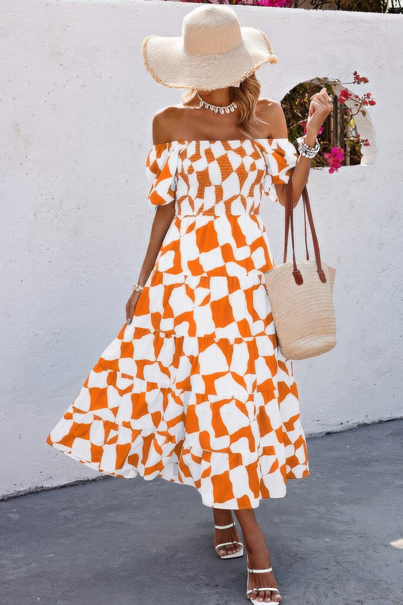Woman wearing off shoulder ruched ruffle dress orange white geometric midi with straw hat woven tote and sandals