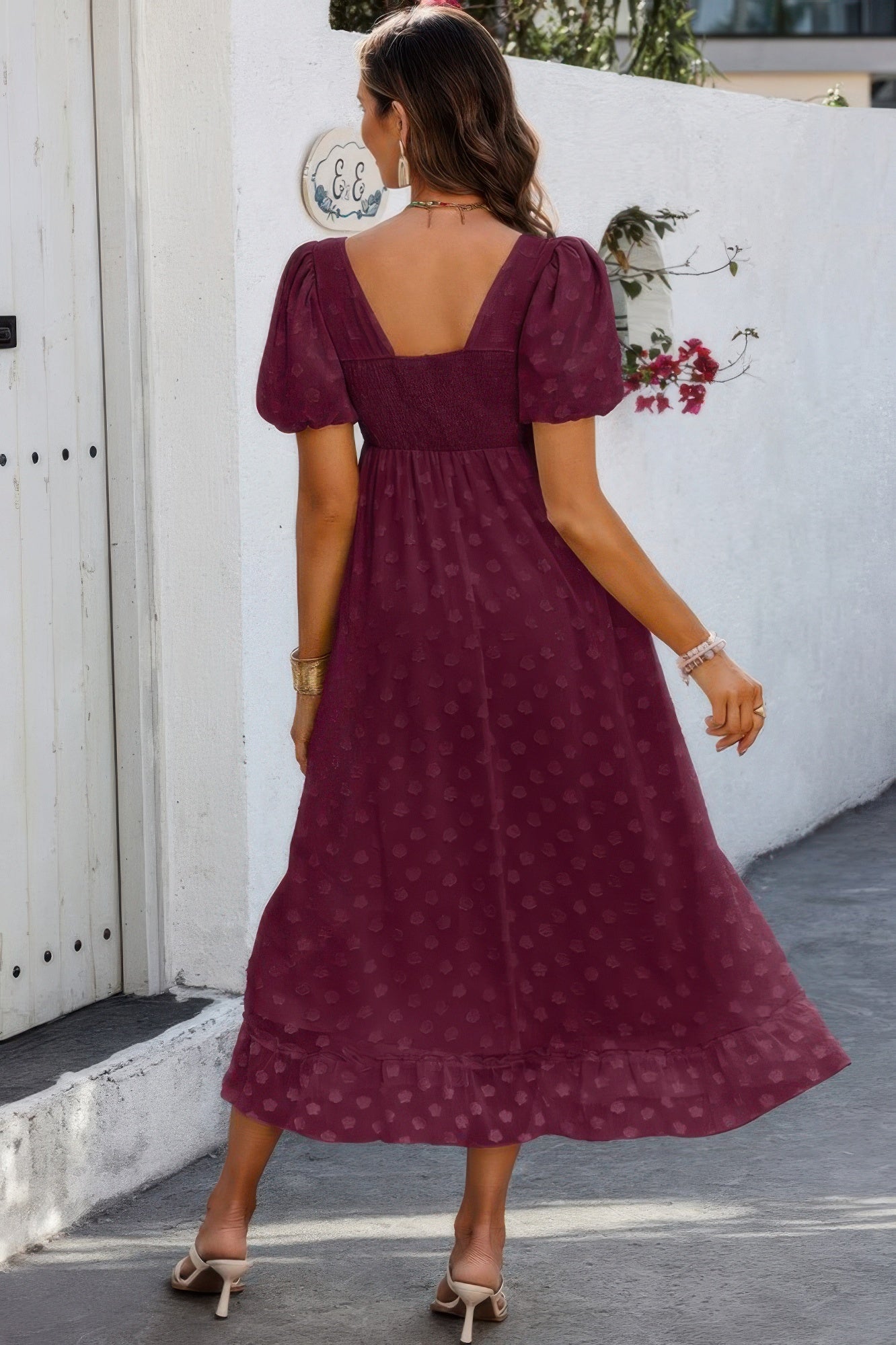 Back view of woman wearing burgundy square neck swiss dot dress with puff sleeves and midi length