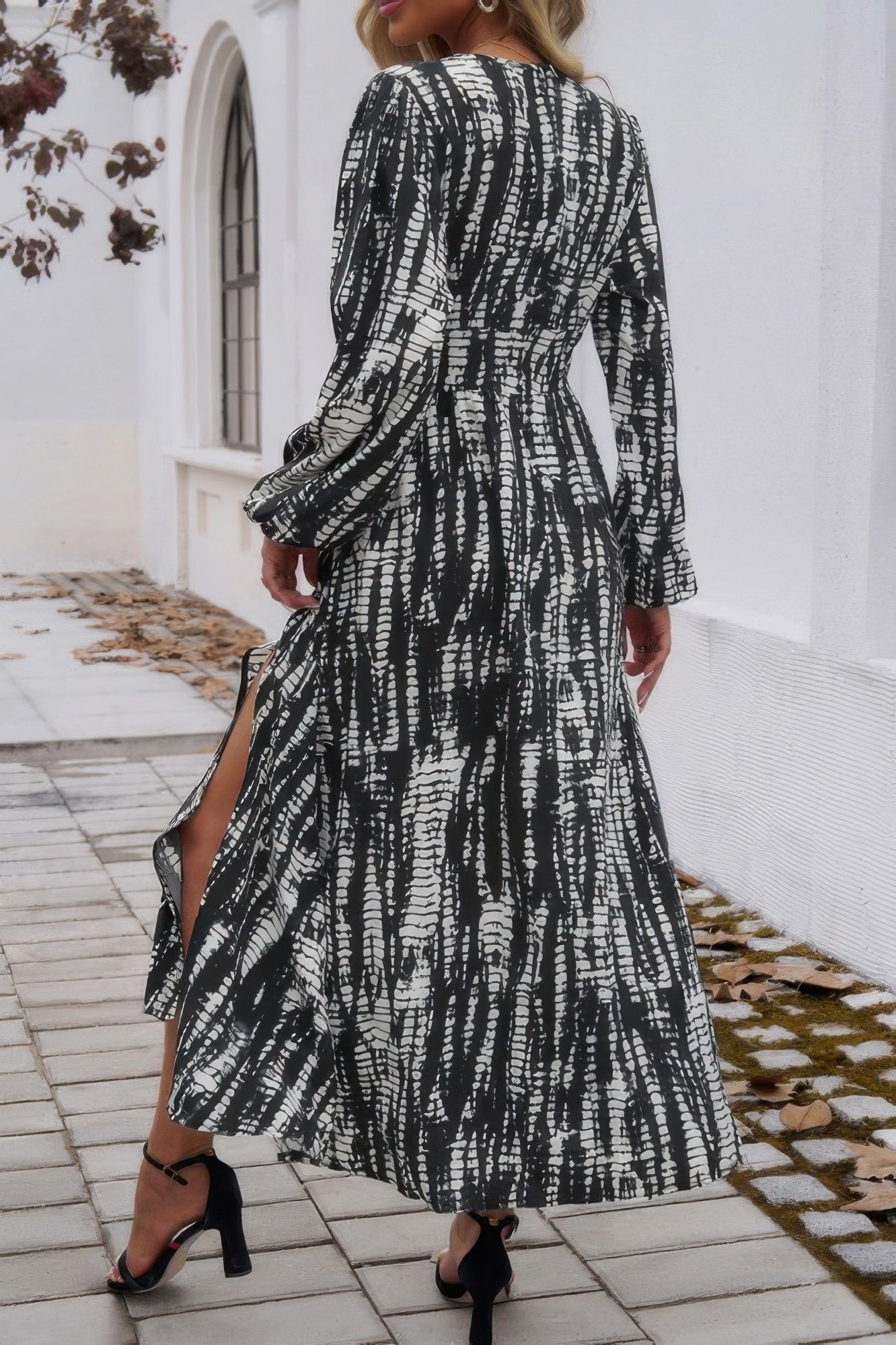 Woman wearing black and white printed Tie Waist Fit Long Dress with long sleeves side slit and heels