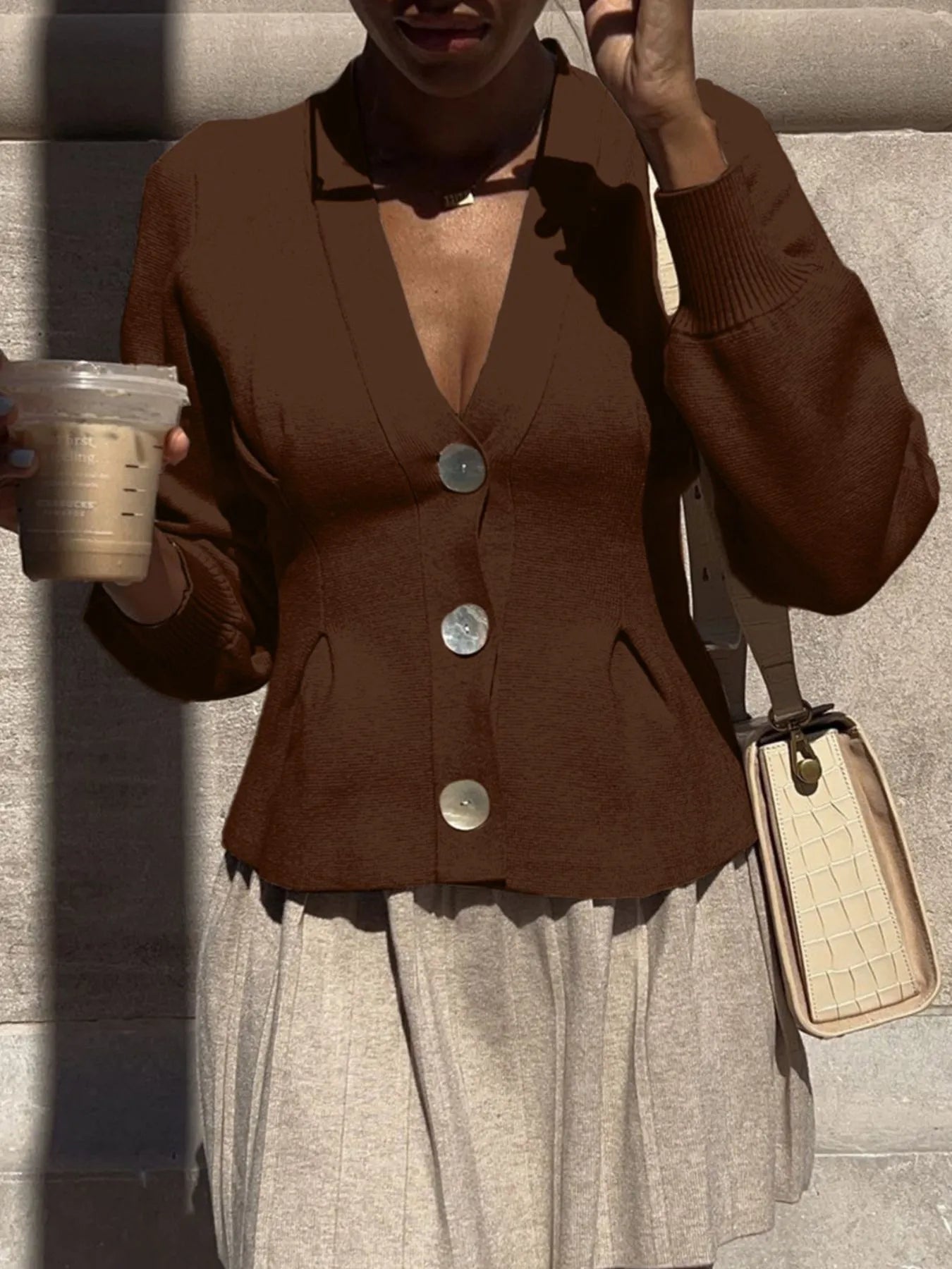 Brown women's button-up knit cardigan with large metal buttons collared V neck balloon sleeves styled with pleated skirt