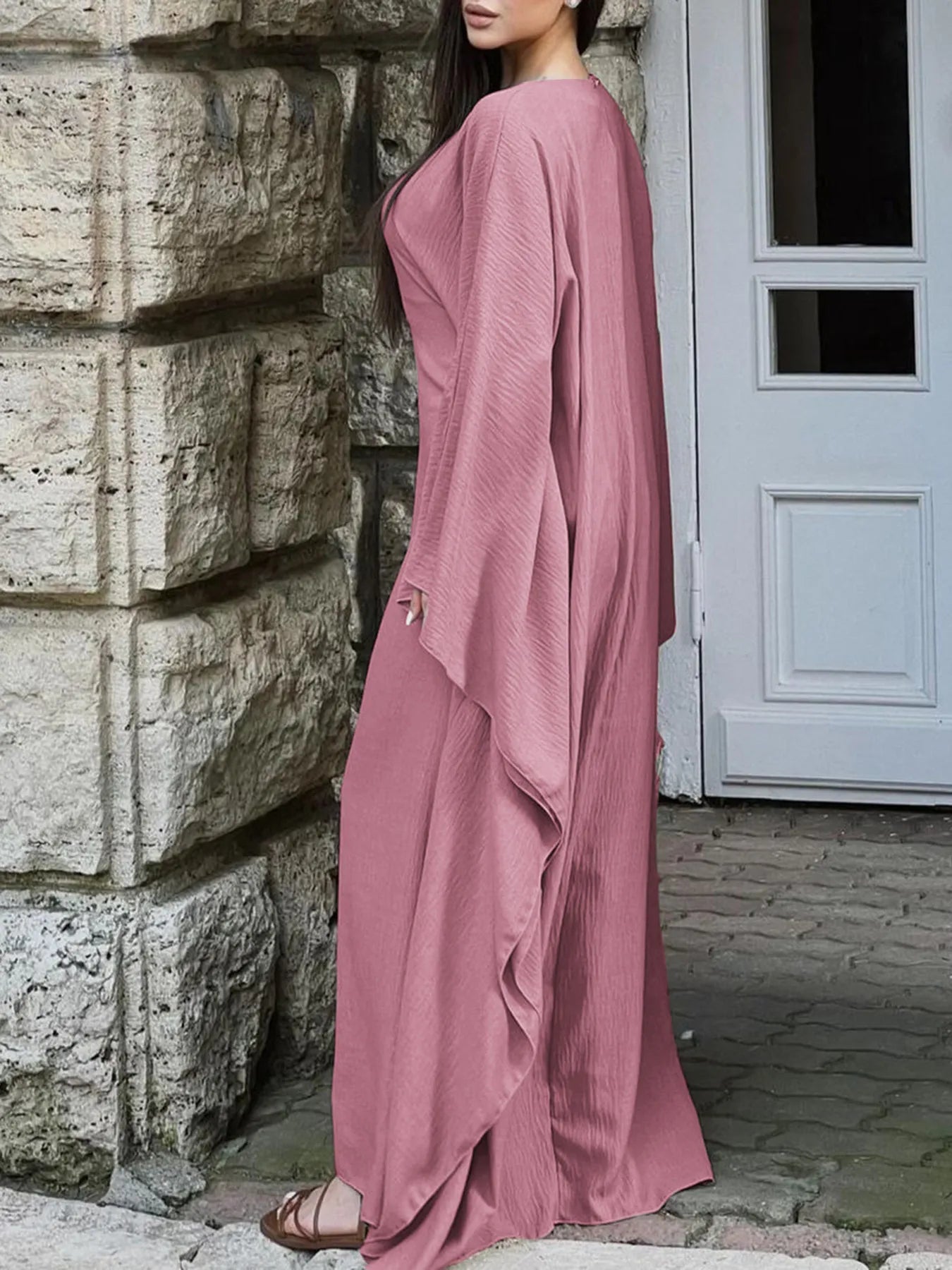 Trendsi bohemian maxi dress with cape sleeves dusty rose side view on model by stone wall