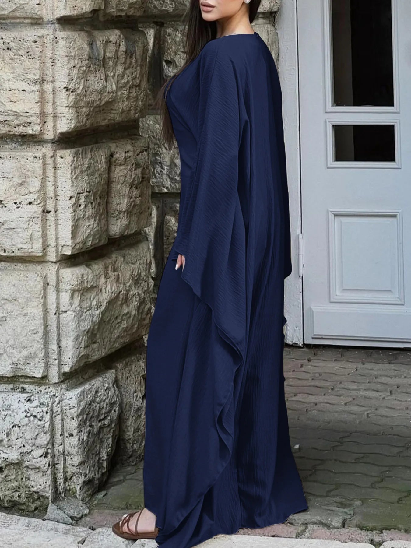 Trendsi navy bohemian maxi dress with cape sleeves side view on model by stone wall and door