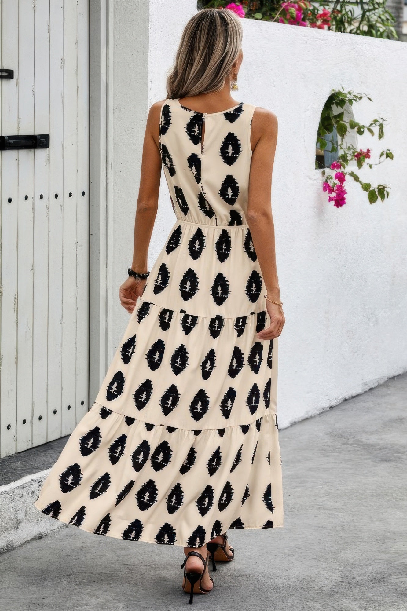 Woman in sleeveless beige maxi with black pattern Elastic Waist Ruffle Full Dress, tiered ruffle skirt and sandals back view