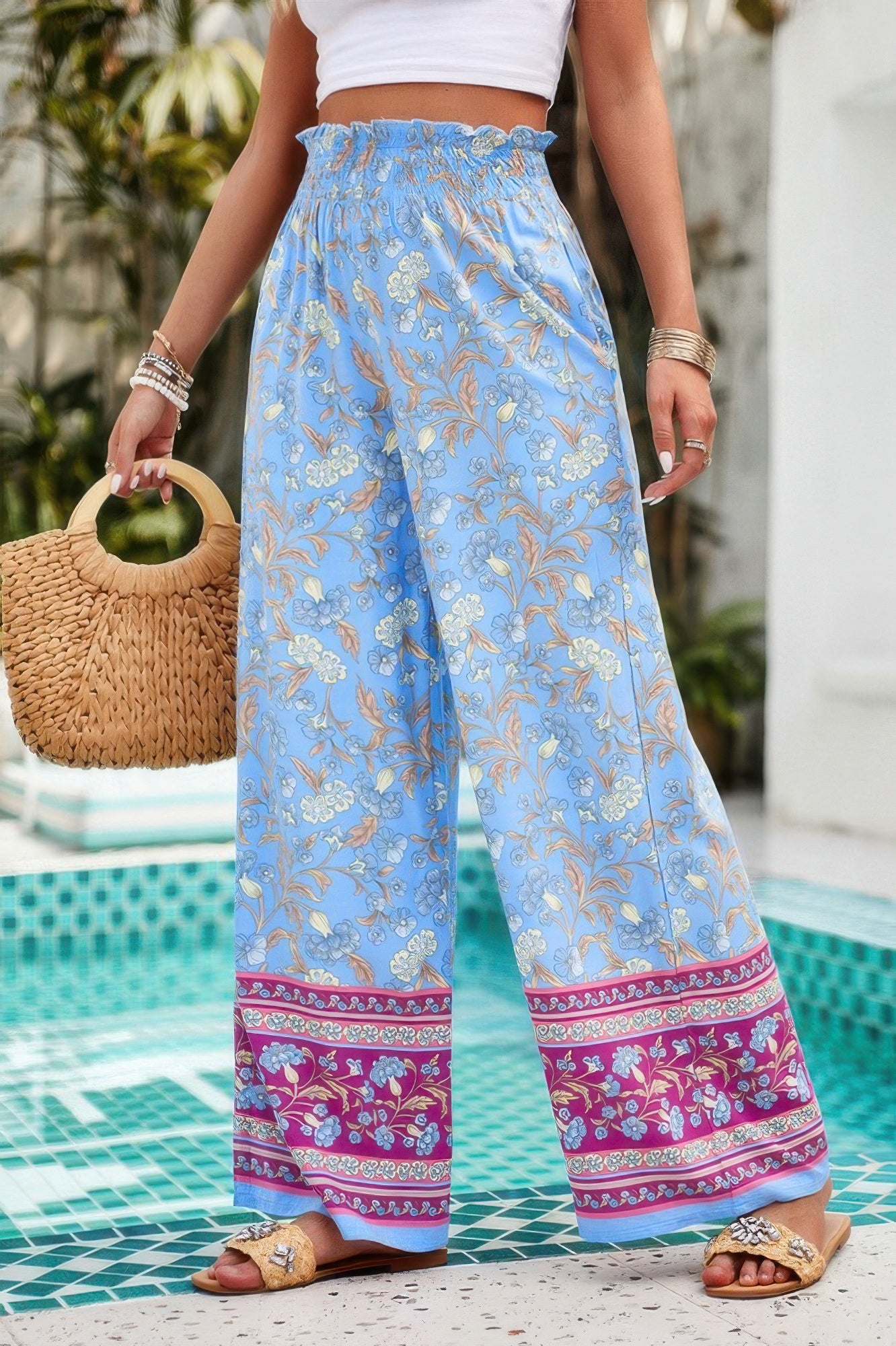 floral wide leg pants for women in sky blue with smocked waist and pink border worn poolside