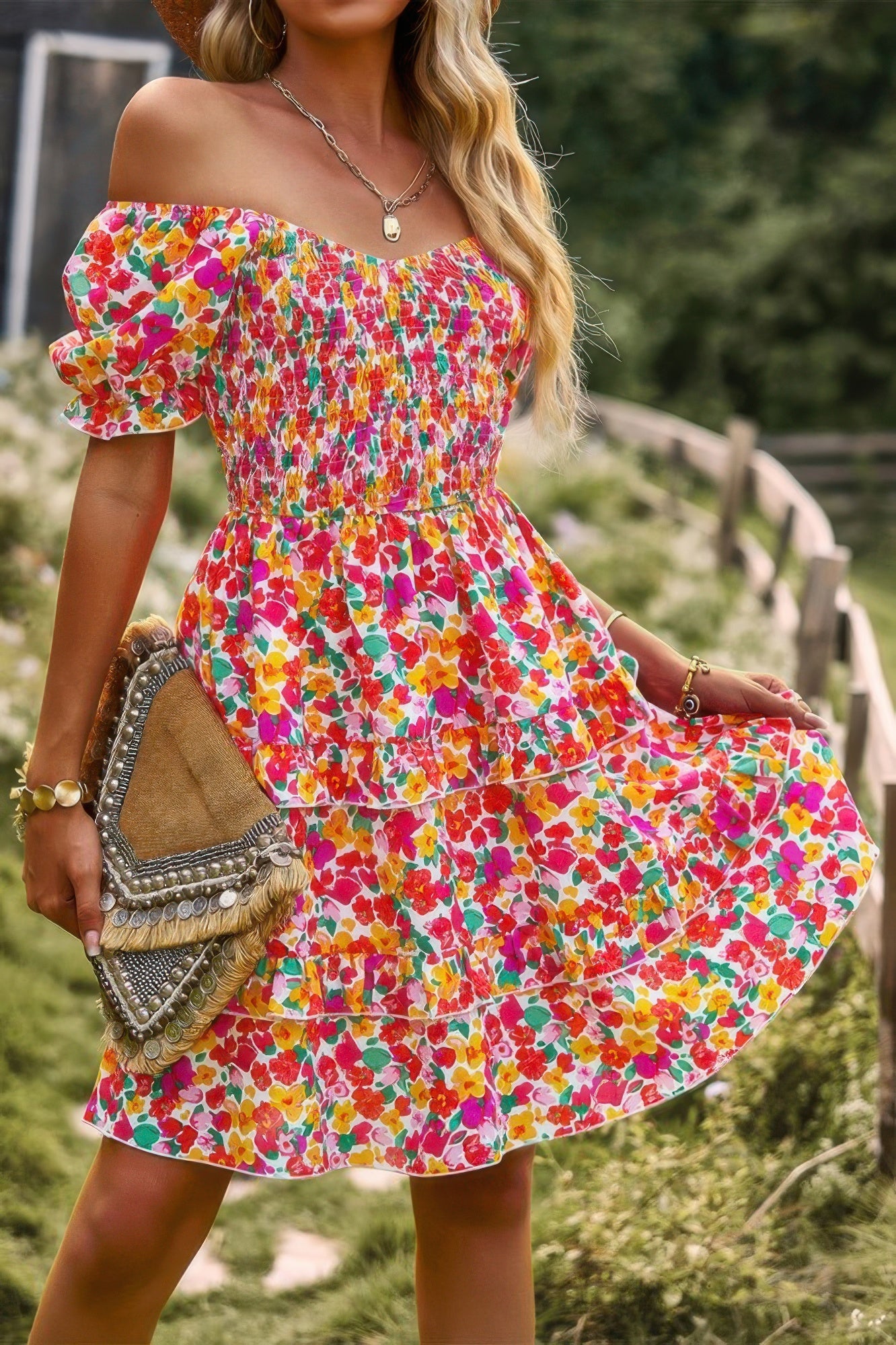 Woman wearing a colorful floral print off shoulder dress with smocked bodice puff sleeves and tiered skirt