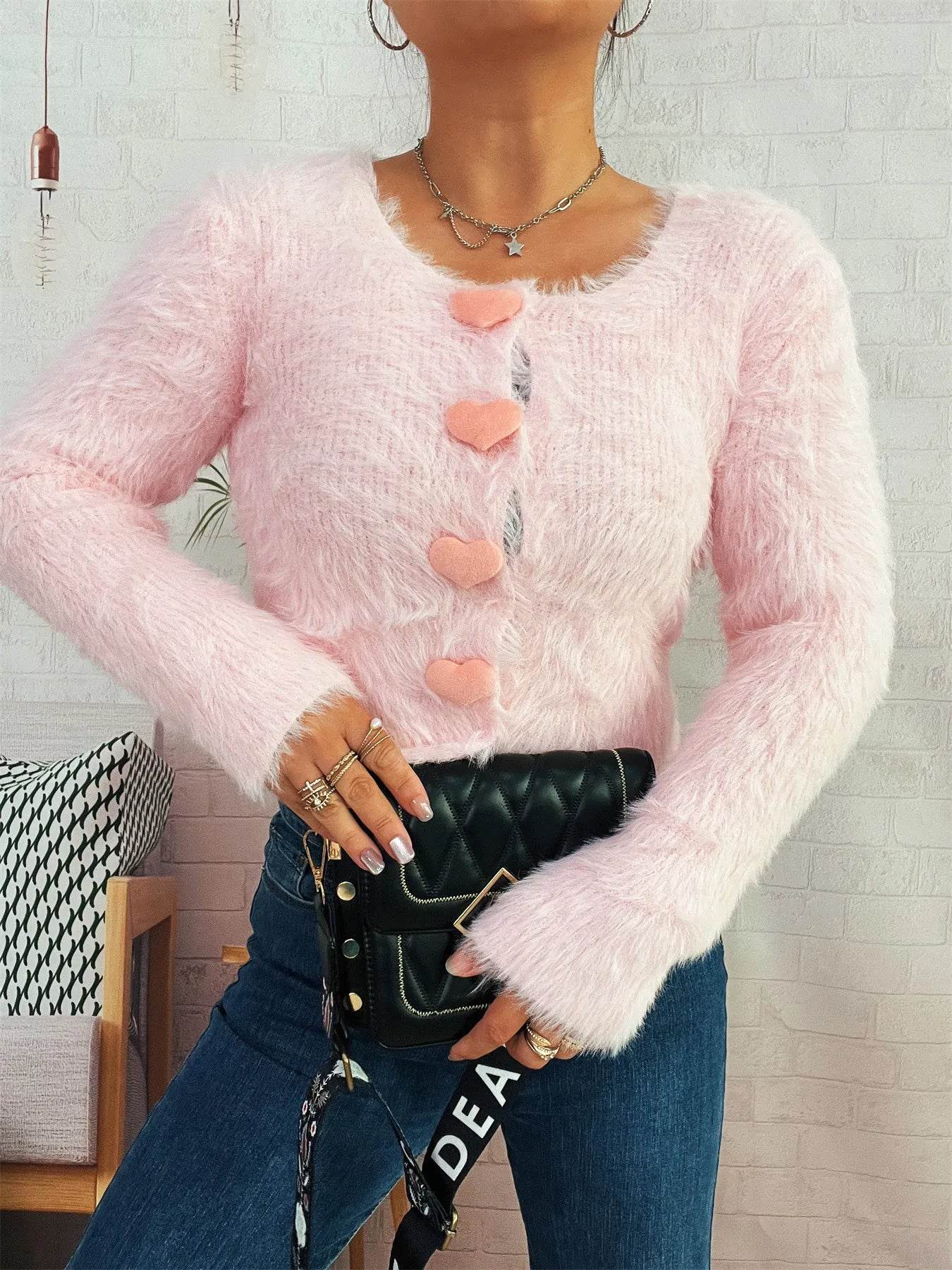 Trendsi pink fuzzy cardigan with heart buttons Cozy Knit Sweater cropped long sleeves styled with jeans and black quilted clutch