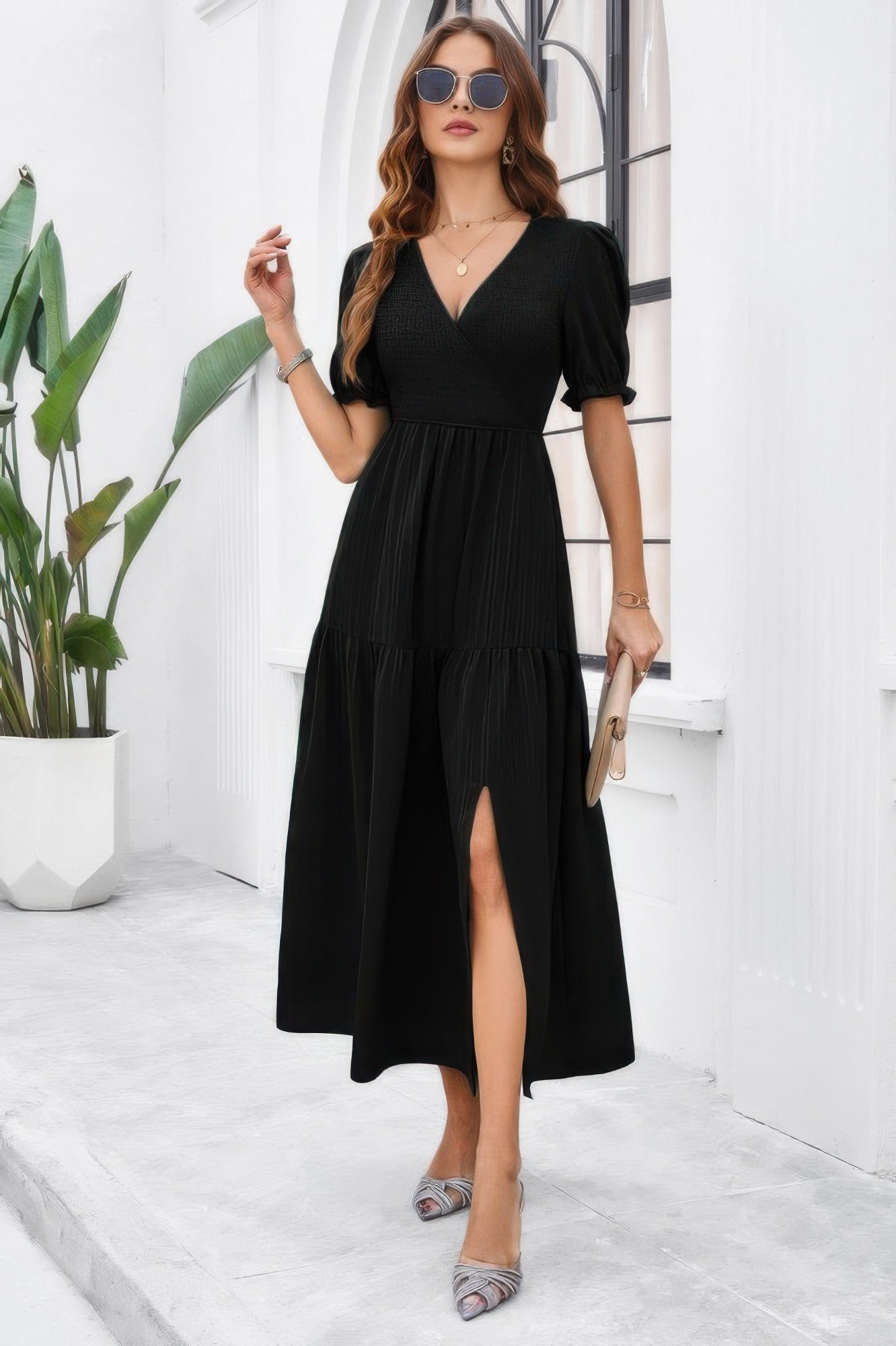 Woman wearing black High Waist Puff Sleeve Dress with V neck tiered skirt and front slit styled with heels