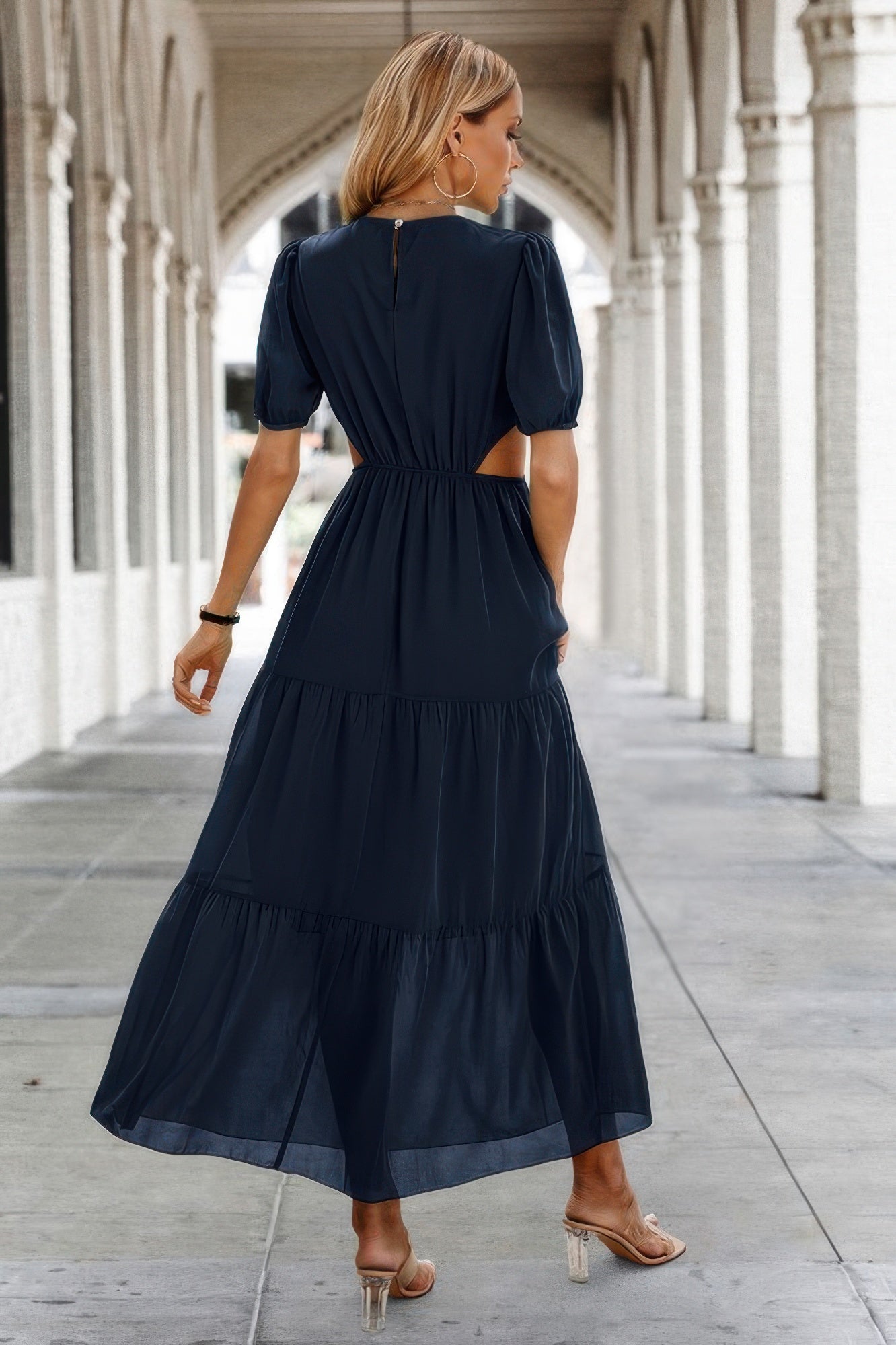 Woman in navy tiered maxi Puff Sleeves Fit Dress with waist cutouts and keyhole back wearing sandals