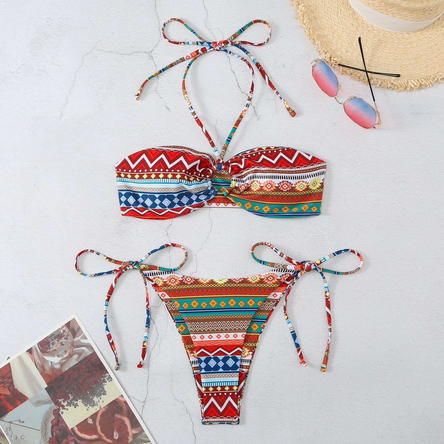 Colorful Halter Split Self Tie Bikini with geometric patterns from Trendsi laid flat with sunglasses and a hat
