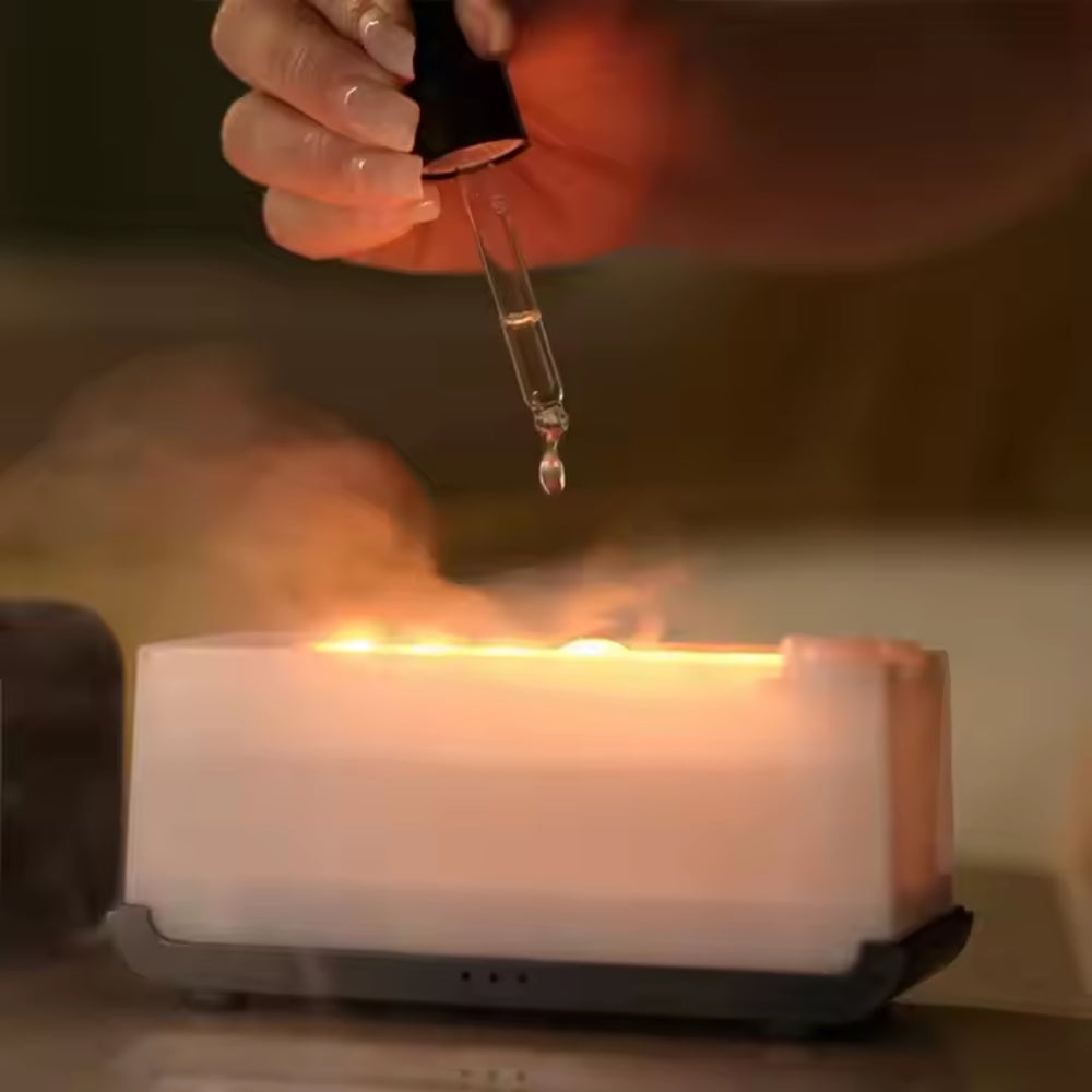 Fashions Envy Flame Aromatherapy Humidifier glowing with warm flame effect and mist as hand adds oil