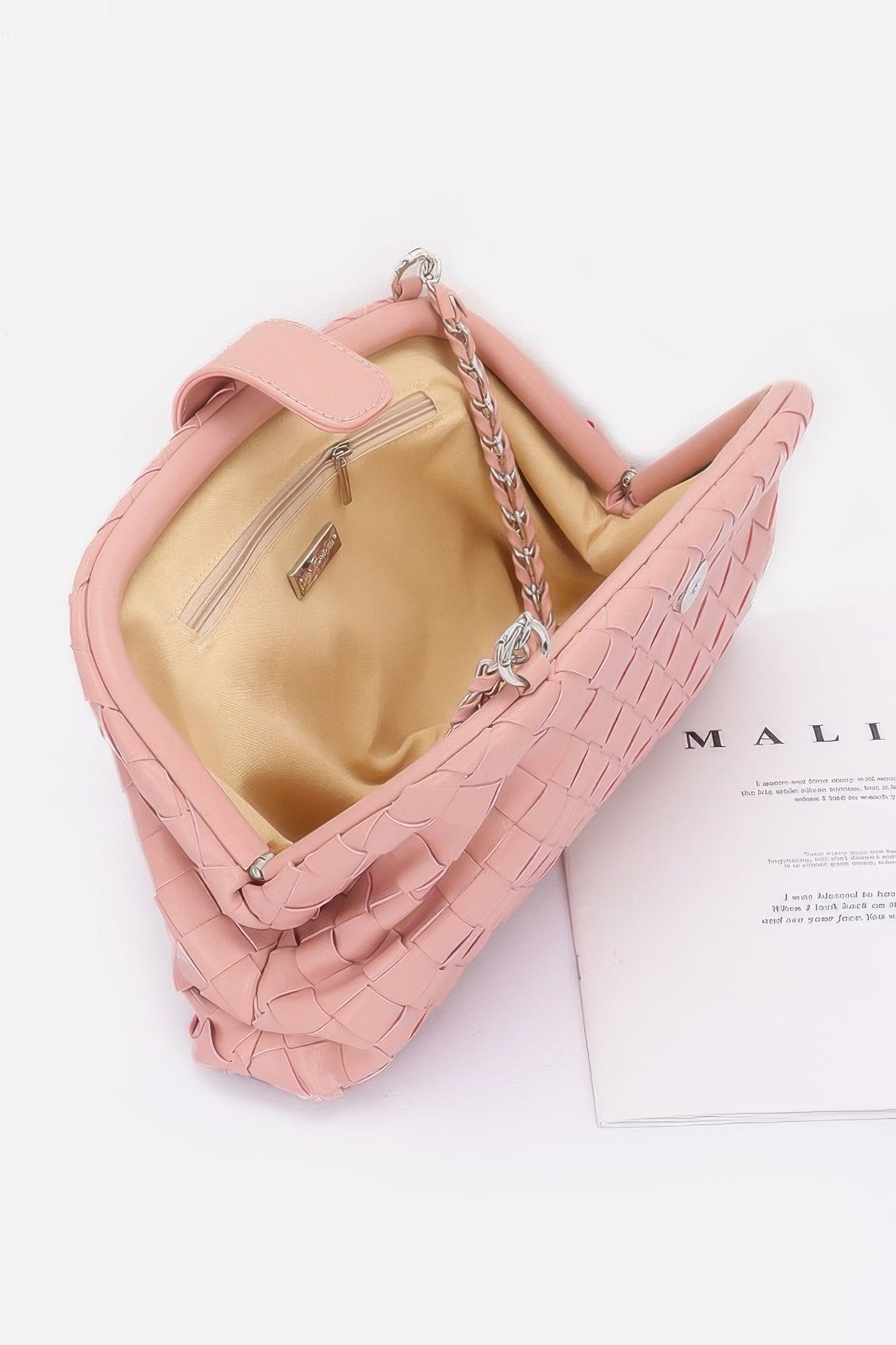 Pink faux leather braided shoulder bag with silver chain strap and beige interior pocket open top view