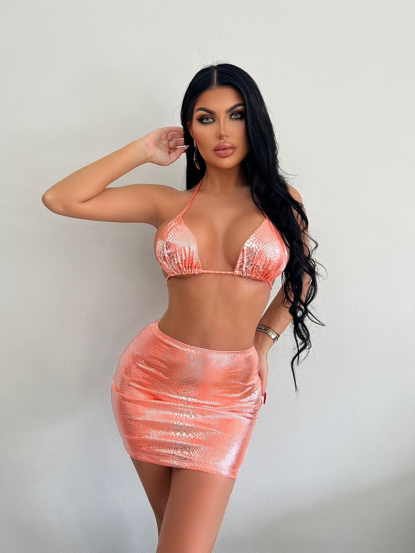 Trendsi model wearing a Metallic Three-Piece Bikini Swimsuit in shiny peach with mini skirt and halter top