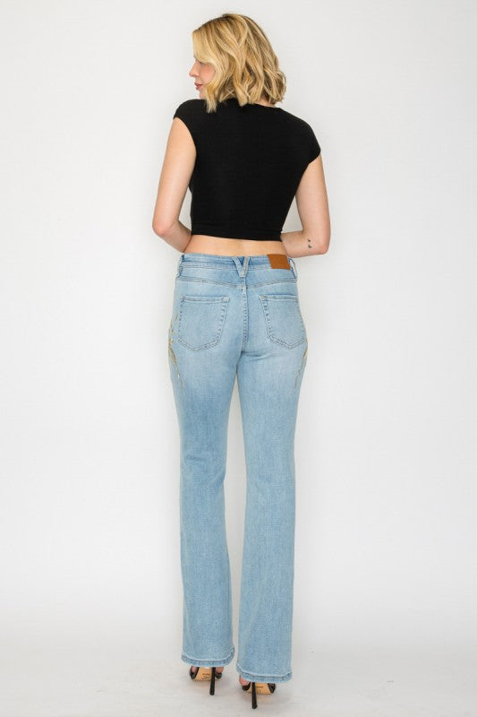 Artemis Vintage model wearing women's high rise embroidered bootcut jeans in light wash back view with floral embroidery