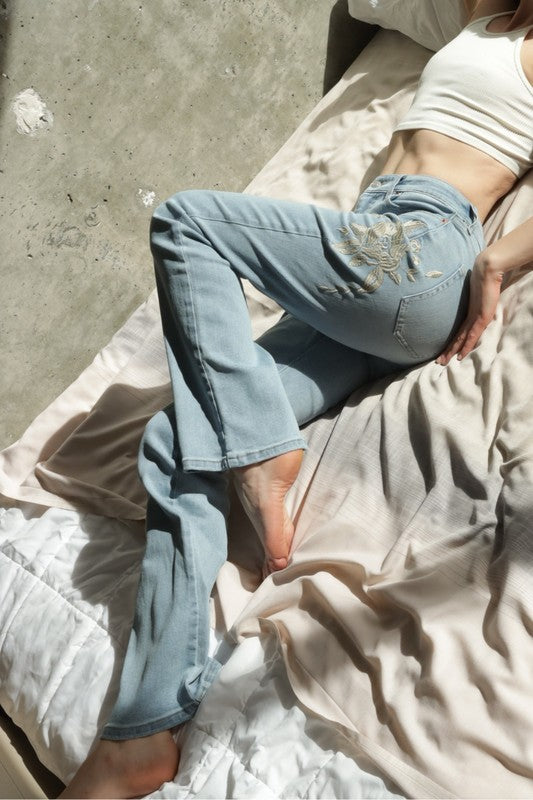 Artemis Vintage women's high rise embroidered bootcut jeans light wash on model reclining with white crop tank