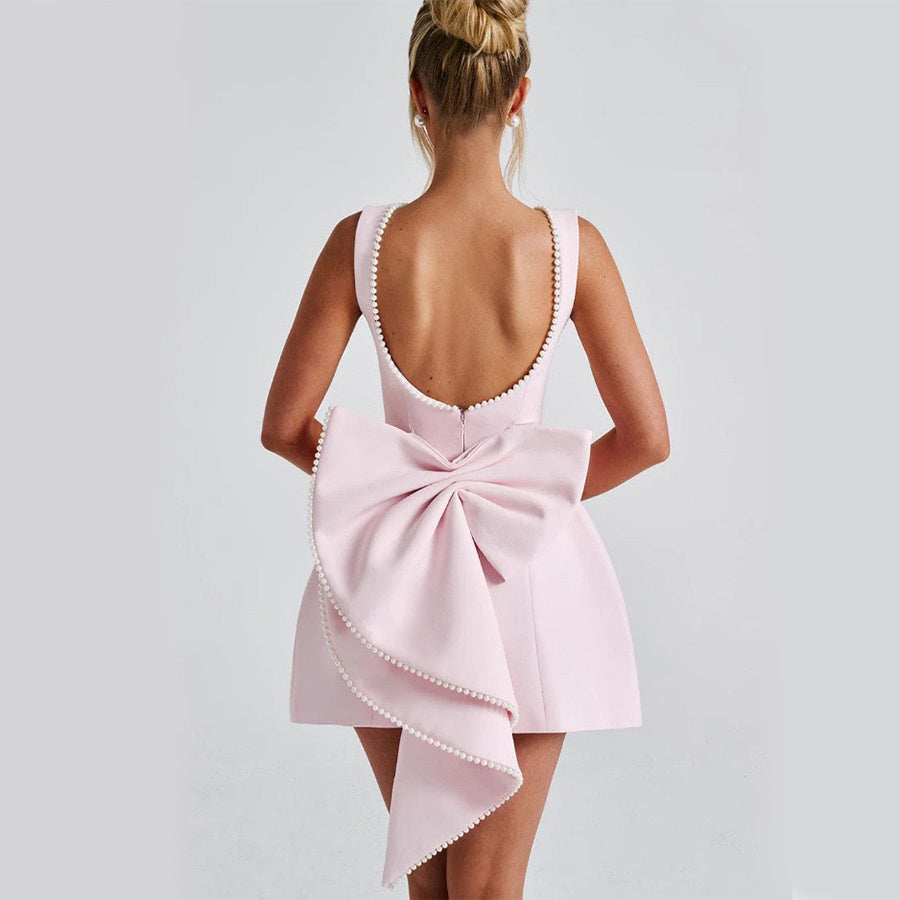 Back view of a Solid Color Mini Dress in pink with a large bow detail for a stylish look