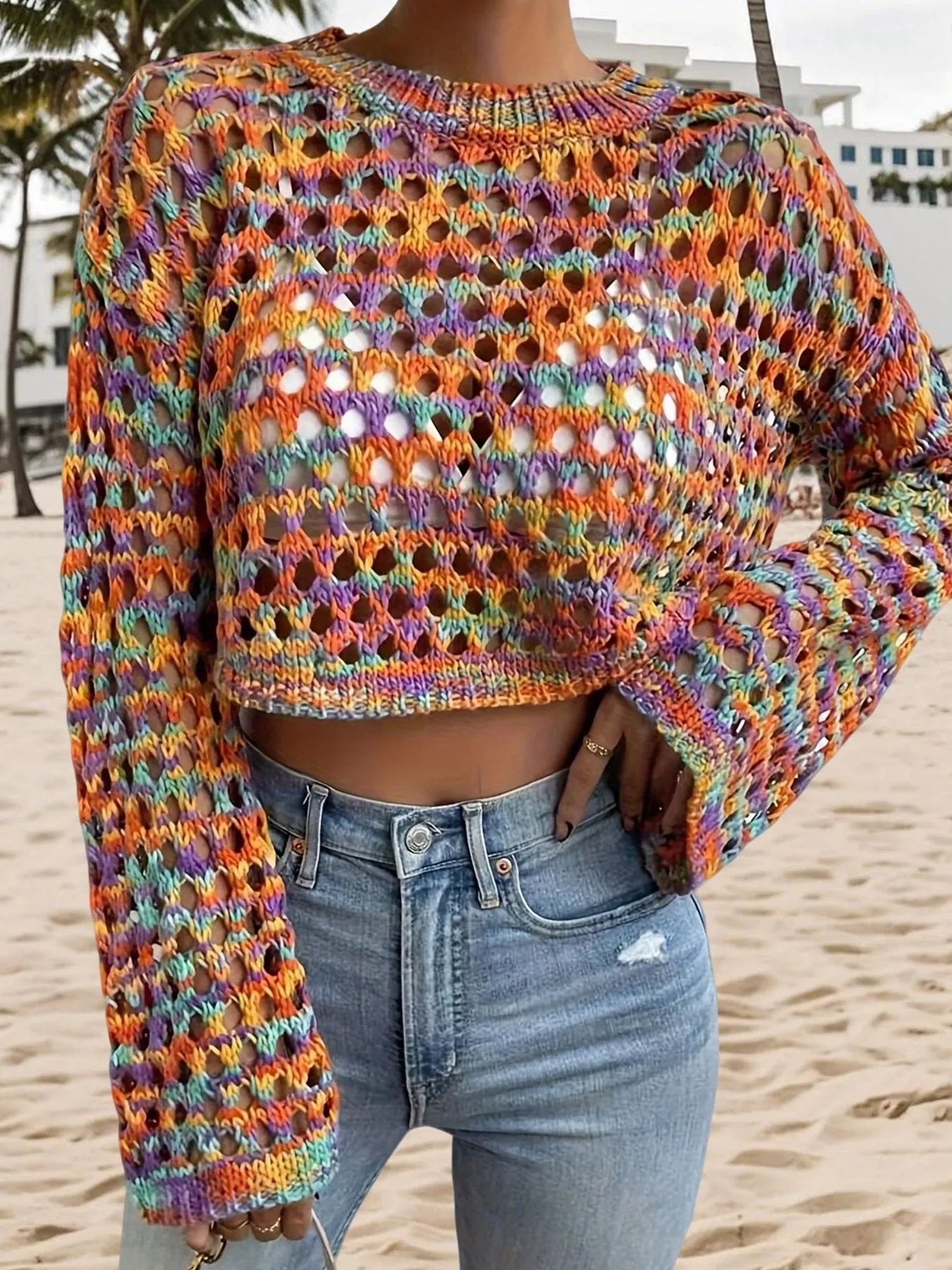 Trendsi Hollow Out Cropped Sweater multicolor open knit long sleeve crop top styled with high waisted jeans on beach