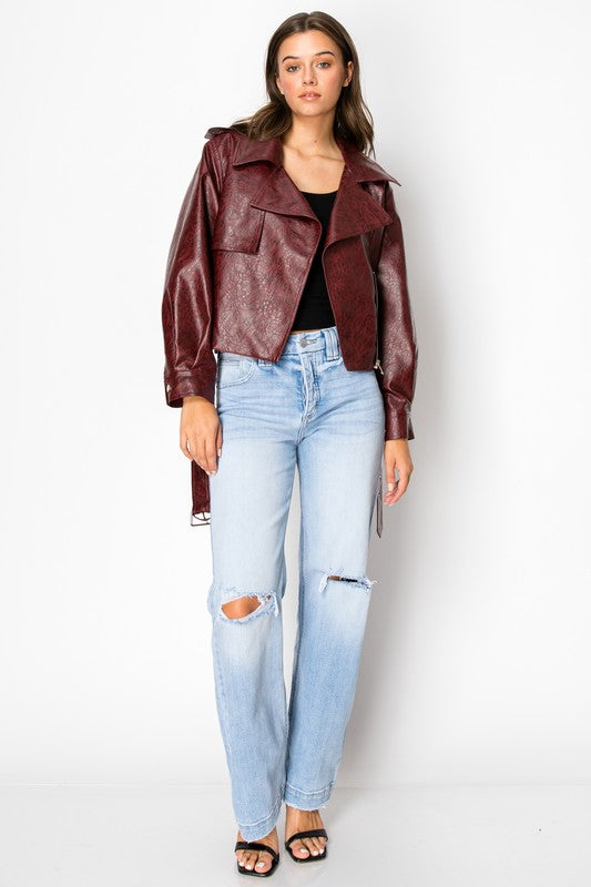 Artemis Vintage model wearing light wash ripped women's tummy control jeans with burgundy leather moto jacket and black tank