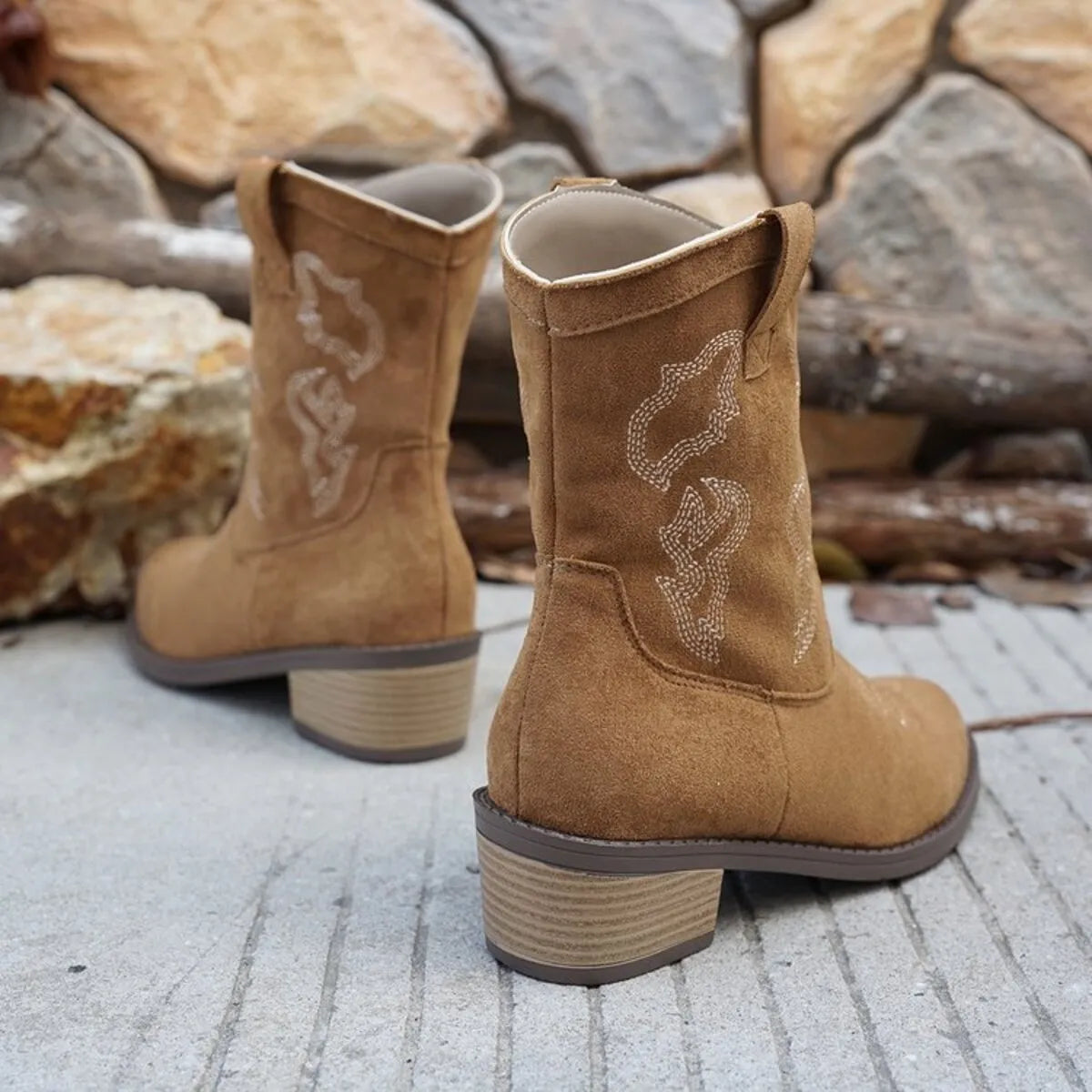 Trendsi suede cowboy boots in tan with stitched design and low stacked heel on stone background