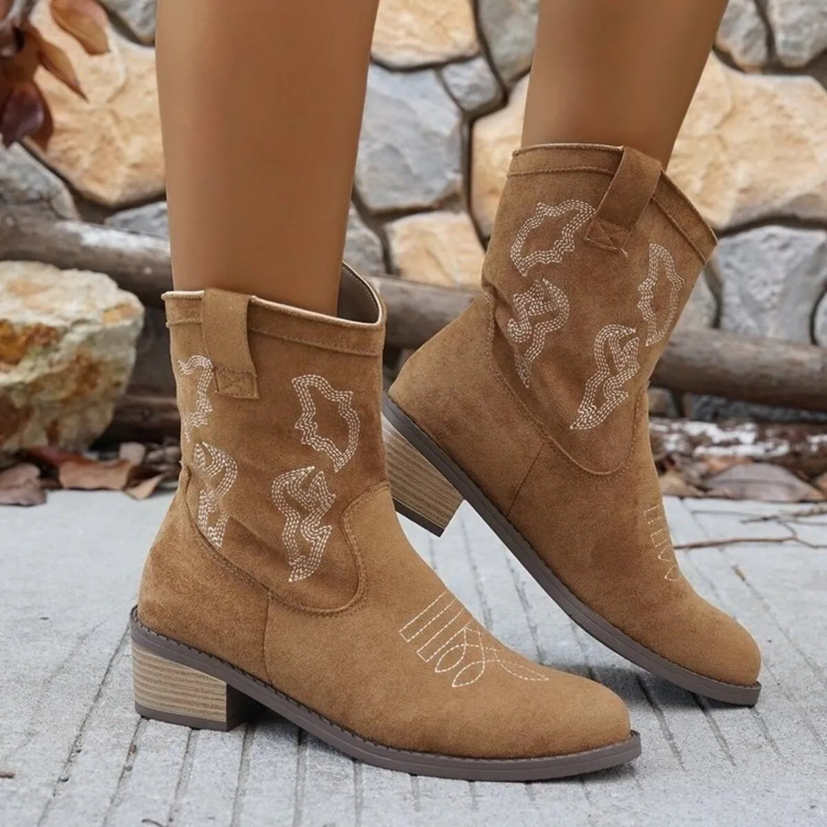 Trendsi tan suede cowboy boots with embroidered details and block heels on concrete ground