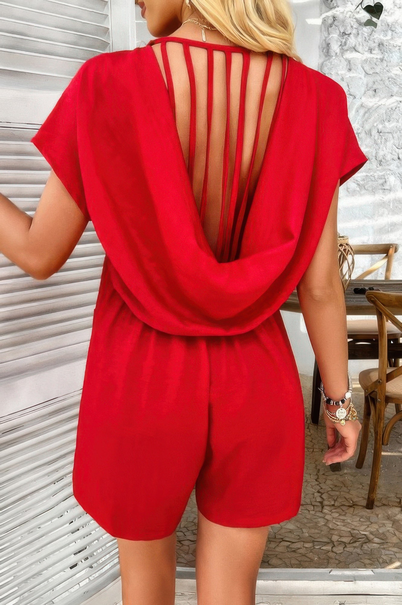 Back view of woman wearing red Loose Pockets Romper with draped cowl and vertical strap details