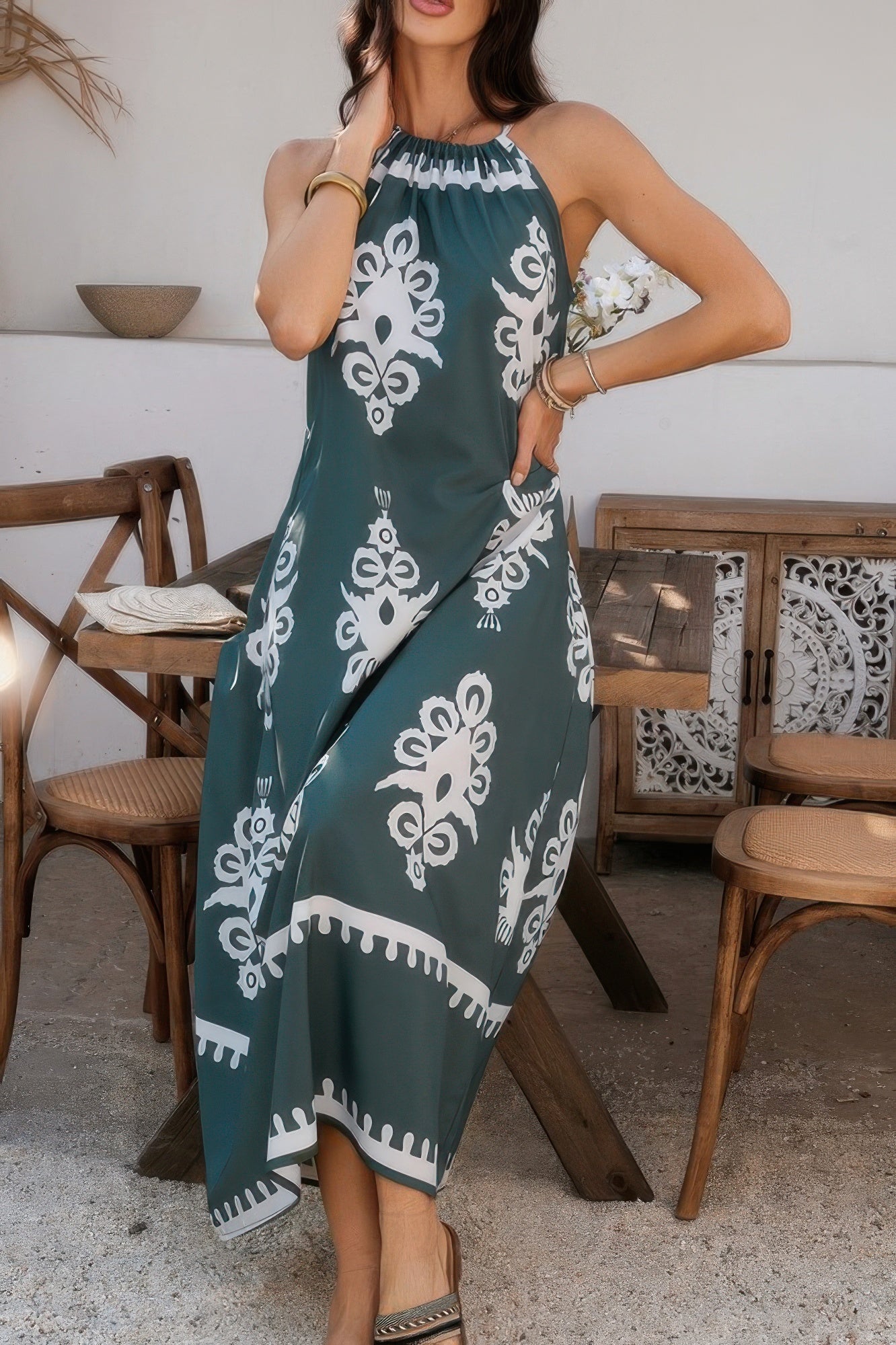 Model wearing teal maxi geo print halter dress with white ornamental motifs for summer resort