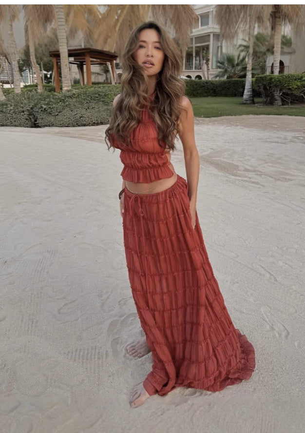 Model wearing a Trendy Halter Top & Maxi Skirt in rust color on the beach