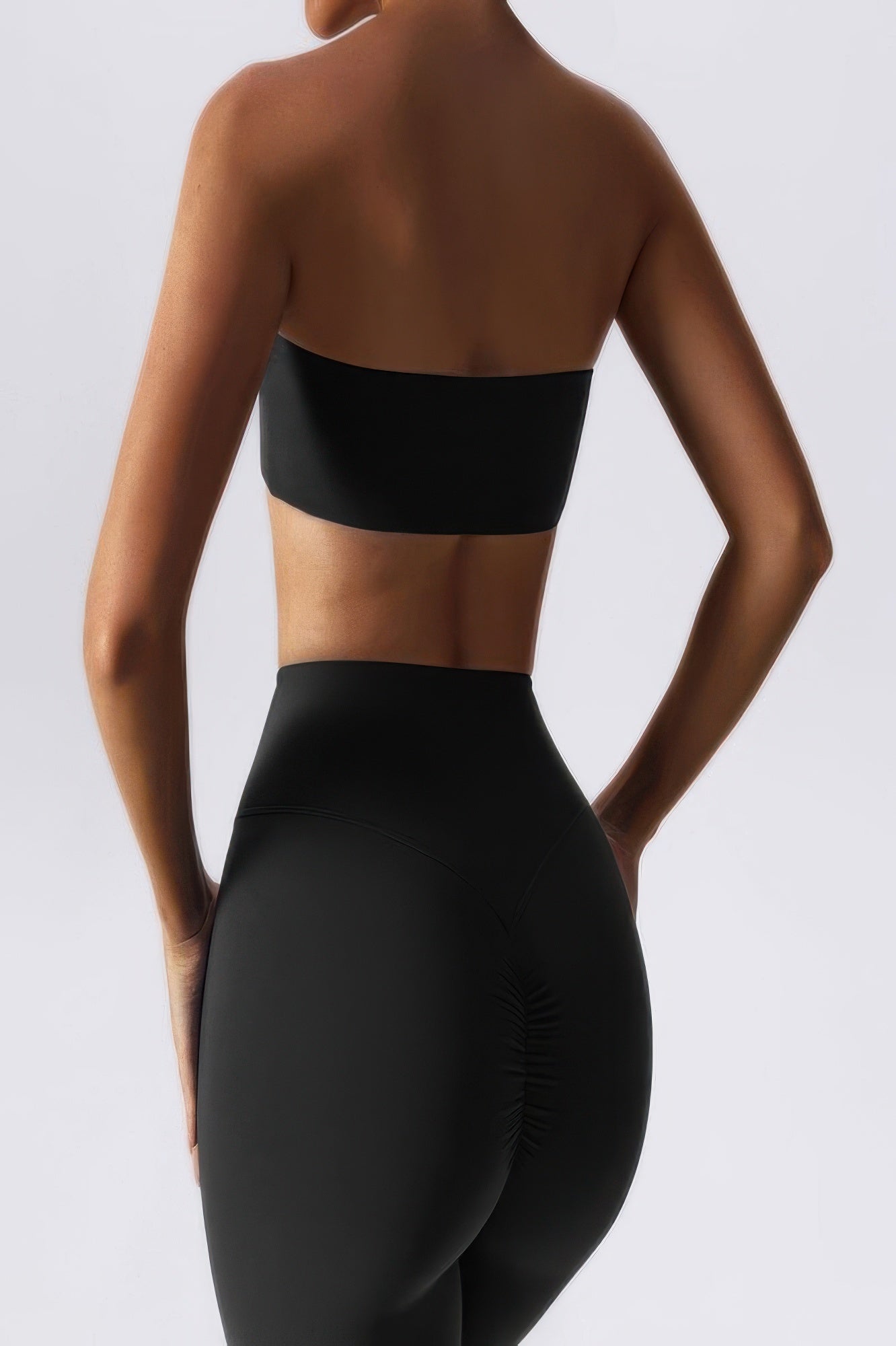 Back view of woman wearing black strapless tube bra for women with seamless high waist leggings for smooth silhouette