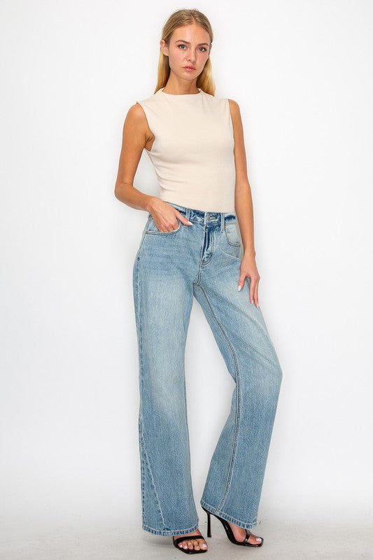 Artemis Vintage model wearing women's mid rise flare jeans light wash with beige sleeveless top and heels