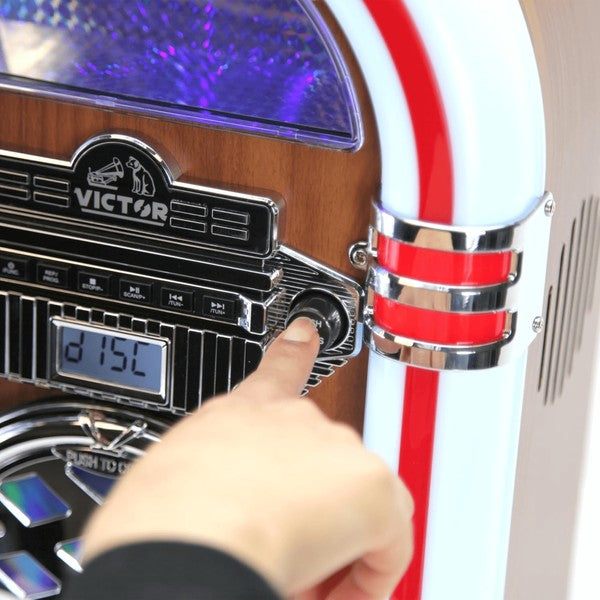 Close-up of a hand adjusting controls on a Victor Broadway II Desktop CD Jukebox with wood and chrome finish