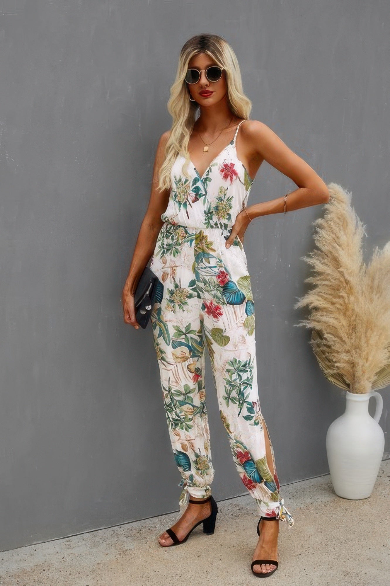 Model in CCWHOLESALECLOTHING floral v neck spaghetti strap jumpsuit with tie waist ankle ties side slits and black heels