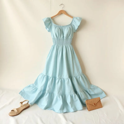 Mint blue smocked tiered midi dress with a fitted bodice and flowing tiered skirt in soft daylight