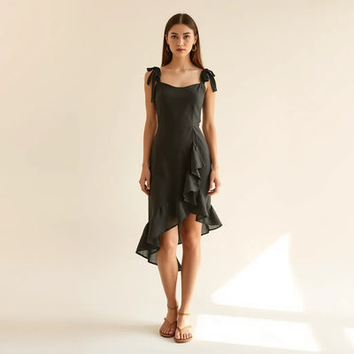 Woman wearing an asymmetrical ruffle hem tie shoulder mini dress with visible layered ruffles and tie straps