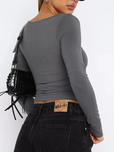 Woman wearing a trendy fitted tee in gray, paired with high-waisted black jeans and a stylish handbag