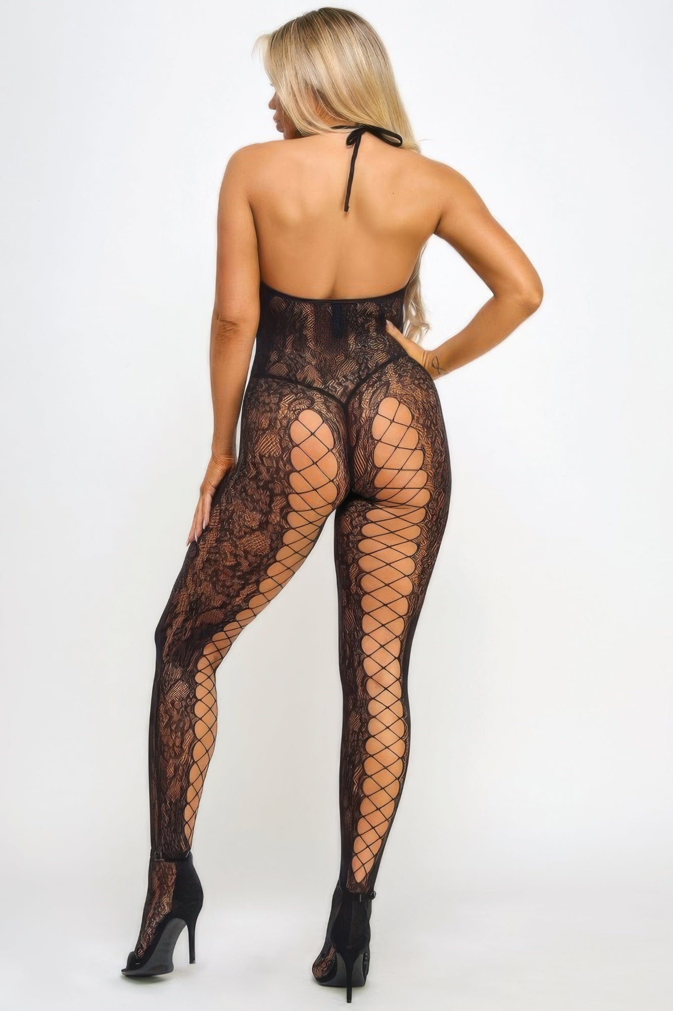 Back view of blonde model in black lace bodystocking for women with halter neck open back and fishnet legs