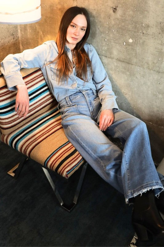 Artemis Vintage model lounging in light wash denim shirt and eco-friendly high rise palazzo jeans with frayed hem