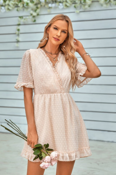 Woman wearing CCWHOLESALECLOTHING swiss dot ruffle midi dress in ivory with puff sleeves and ruffle hem holding flowers