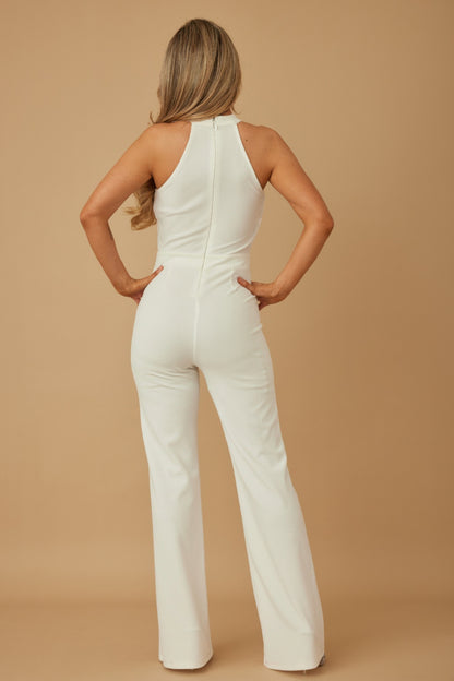 Back view of model wearing white halter chain jumpsuit with zip back fitted bodice and wide leg trousers