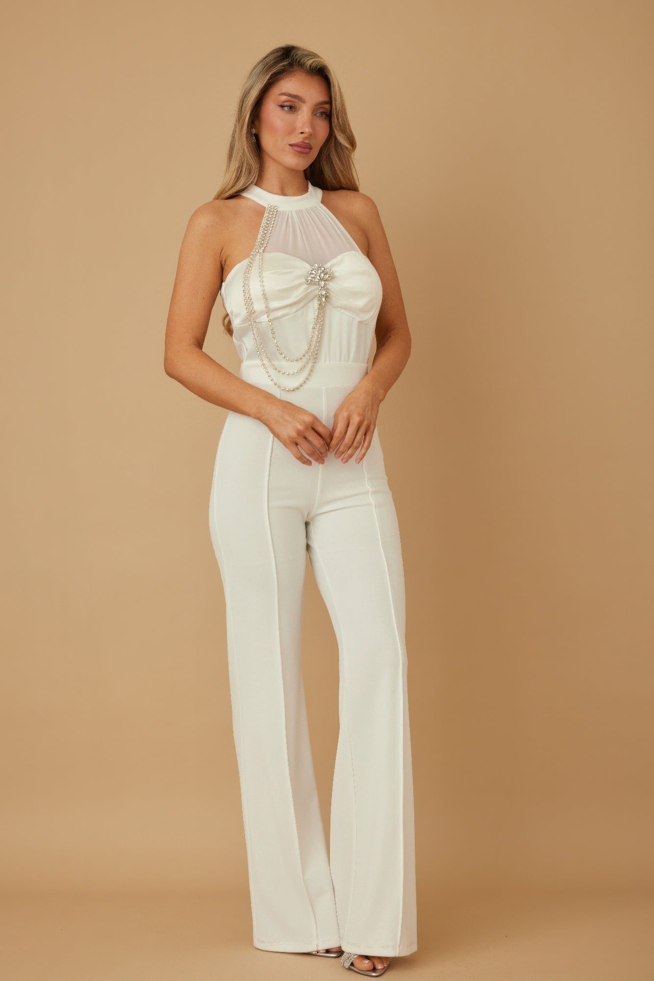 Model wearing CCWHOLESALECLOTHING white halter chain jumpsuit with sheer high neck chain drape and flared pants