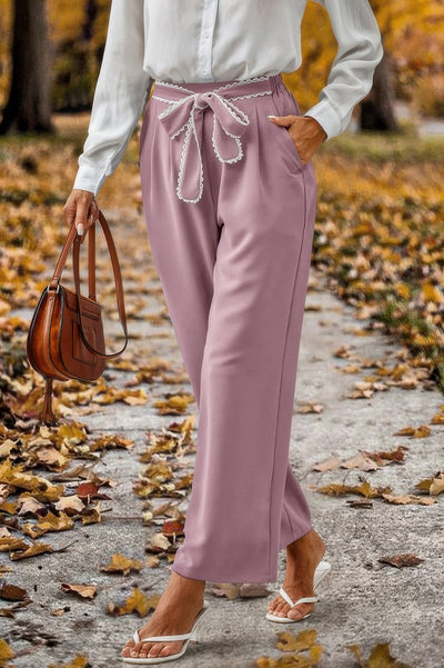 Model wearing mauve high waist straight leg pants for women with braided tie belt and pockets styled with white blouse