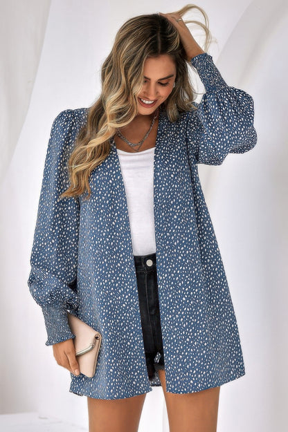Woman wearing blue leopard print front open top with puff sleeves over white tee and black shorts