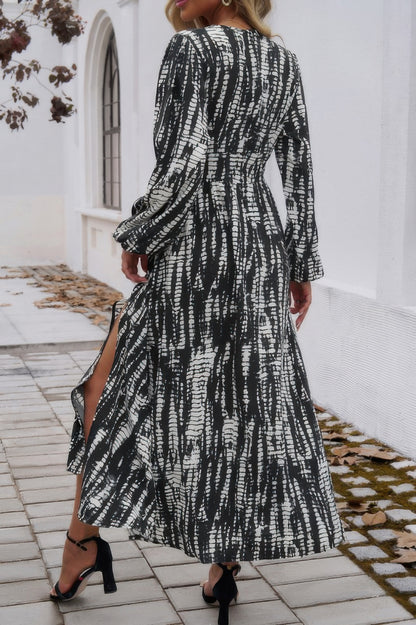 Woman wearing black and white printed Tie Waist Fit Long Dress with long sleeves side slit and heels