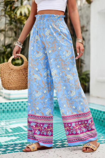 floral wide leg pants for women in sky blue with smocked waist and pink border worn poolside
