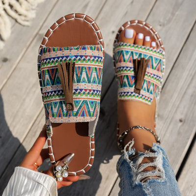 Trendsi Boho Tassel Slide Sandals with colorful geometric pattern and stitched edges on wooden floor