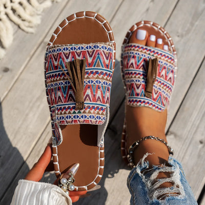 Trendsi Boho Tassel Slide Sandals with colorful geometric pattern and brown tassel detail on wooden deck