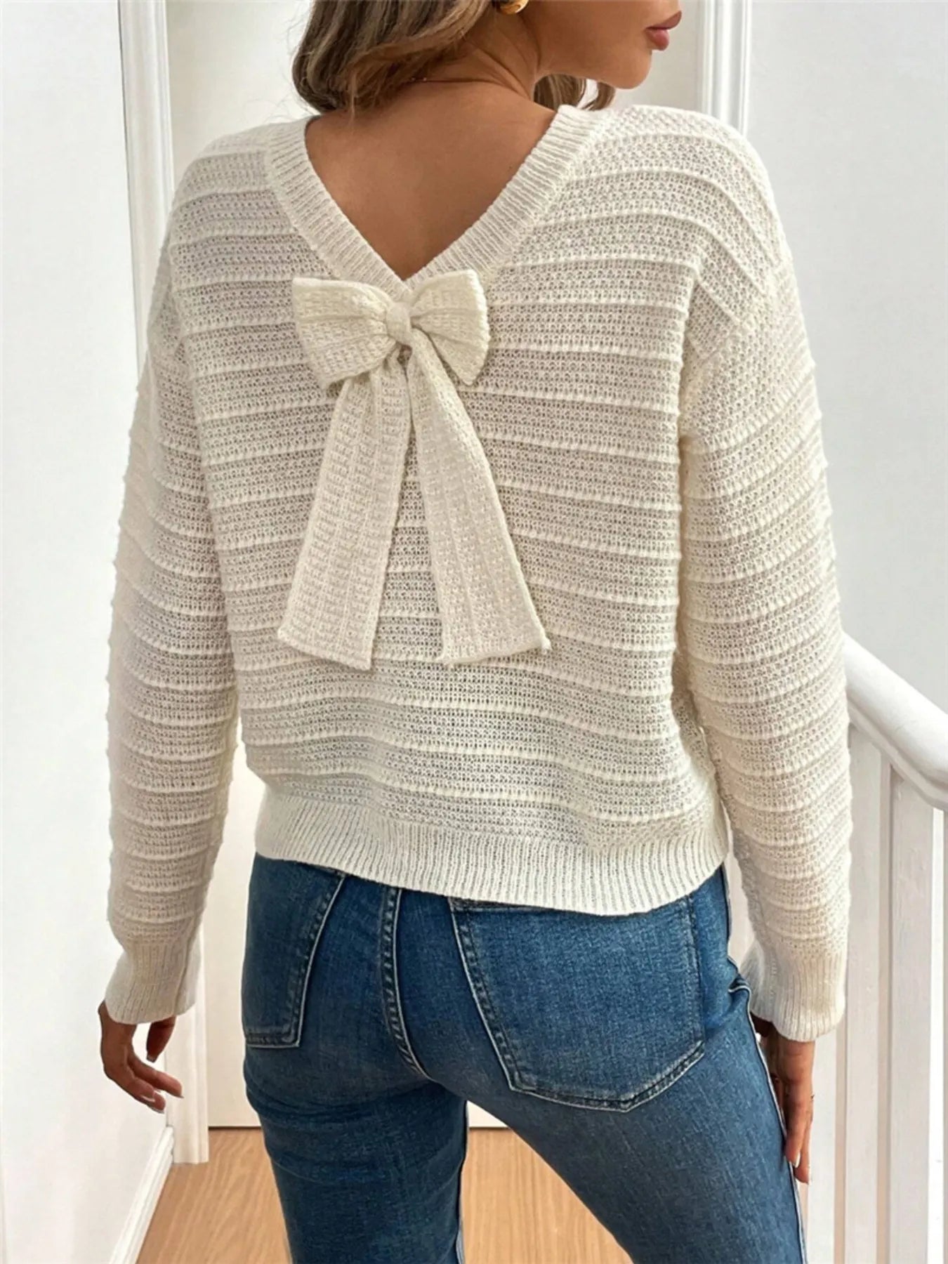 Trendsi Bow-Back Knit Top cream textured knit V back decorative bow shown paired with blue jeans